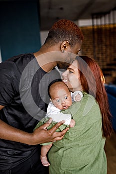 Close up of African American family mixed parents take care of cute baby at home. Caring young father and mother smile