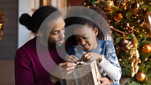 Close up African American father and daughter unpacking Christmas gift