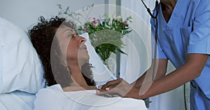 Close-up of African american female doctor examining female patient in the ward at hospital