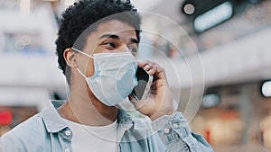 Close-up African American guy in medical face protective mask talking mobile phone answering call talks to doctor