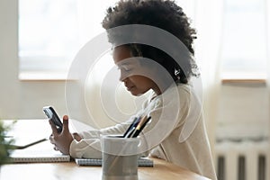 Close up African American little girl holding phone, studying online