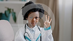 Close-up african american little girl standing in medical clothes playing pretending to be doctor charming child looking