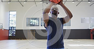 Close up of african american male basketball player shooting ball at indoor court, slow motion