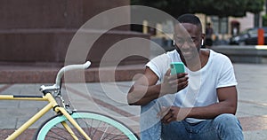 Close up of African American Man in Headphones Using his Smartphone, Touching Screen Looking Happy and Excited while