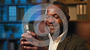 Close-up african american man looking at phone screen playing mobile game browsing social network surprised excited