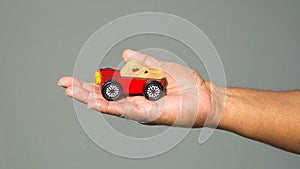 Close up of African American man`s hand holding a toy car against a solid background