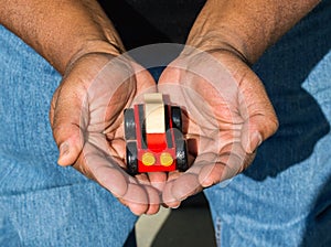 Close up of African American man`s hands cupped around a toy car viewed from above