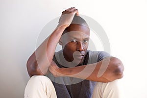 Close up african american man sitting against white wall and thinking