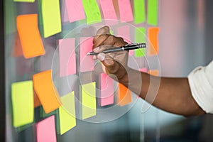 Close up african american manager writing notes on kanban board.