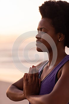 Close-up of african american mature woman with afro hair closing eyes and meditating at beach