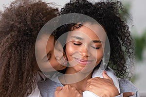 Close up African American teen daughter embracing smiling mother