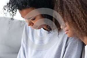 Close up African American teen daughter hugging upset depressed mother