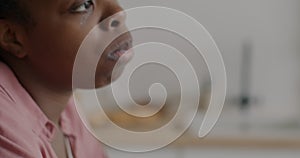 Close-up of African American woman eating cereal with milk enjoying healthy breakfast in kitchen at home