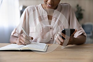 Close up African American woman holding phone, taking notes