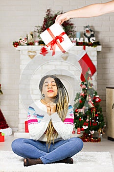 Close up of african american woman make a Christmas wish. New Year decorations and winter holiday home background. Merry Xmas gift