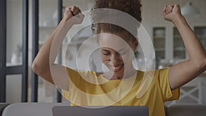 Close up of an African American woman recieving good news celebrating achievement on her laptop