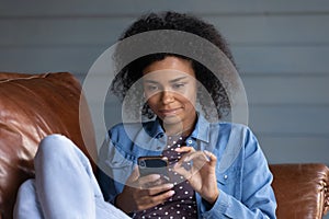 Close up African American woman using smartphone, relaxing on couch