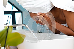 Close up of african american woman washing her face in the sink at home