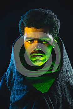 Close-up African-American young man isolated on dark background in neon light.