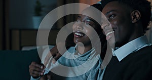 Close-up of African couple in love. Attractive guy and girl sit on sofa and watch melodrama. Their favorite moment is