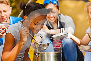 Close-up of African girl cooking soup at campsite