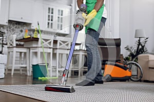 Close up of african janitor cleaning carpet with vacuum