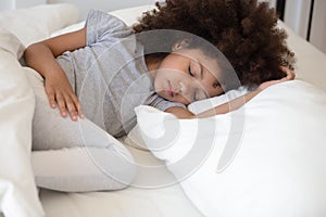 Close up african little girl sleeping in bed at home