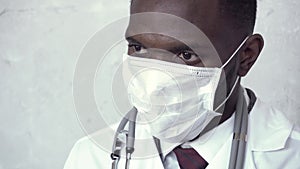 Close up of african male doctor hands, who puts on blue gloves standing against a concrete wall, and then he takes a