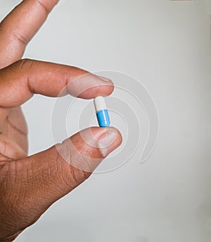 Close up on African male left hand holding a medicine capsule