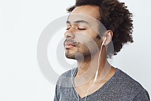 Close up of african man listening to music in headphones with closed eyes.