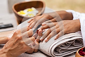 Beautician file nails to a black hand photo