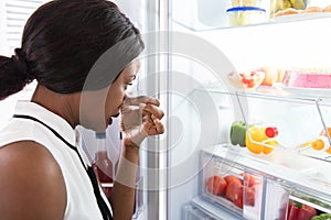 Woman Holding Her Nose Near Foul Food In Refrigerator photo