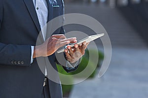 Close up of afro american businessman hands using tablet. A black business man in a formal suit browses the internet mobile device