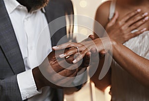 Close up of afro man putting ring on woman finger