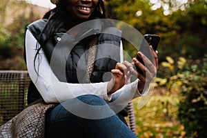 Close up of afro woman using mobile phone while sitting outdoors