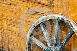 Close-up of age weathered wagon wheel with wooden spokes leaning