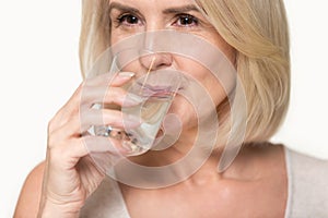 Close up aged attractive woman holding glass drinking water