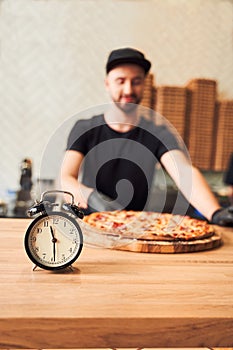 Close up alarm clock with pizza and backer