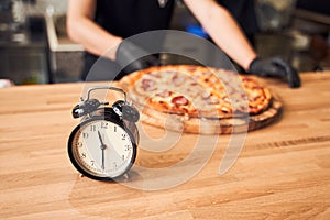 Close up alarm clock with pizza and backer