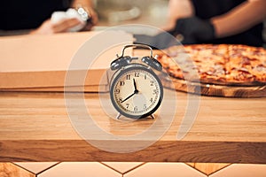 Close up alarm clock with pizza and backer