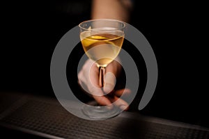 Close-up of alcohol cocktail with lemon rind in bartender`s hand