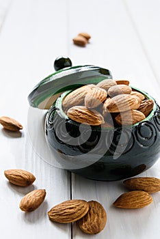 close-up, almonds in a green wooden bowl on a white wooden table