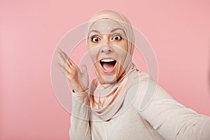 Close up amazed surprised arabian muslim woman in hijab light clothes posing isolated on pink background. People