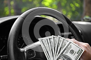 Close-up of american dollars on a wheel. A man driving with money on a car background. Investment and savings concept.