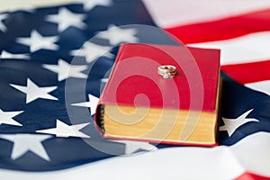 Close up of american flag, wedding rings and bible