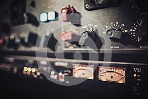 Close-up amplifier equipment with sliders and knobs at boutique recording studio.