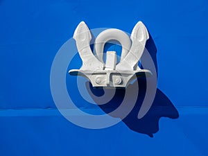 Close up of an anchor on blue a ship`s hull.