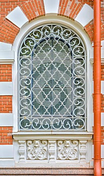 Close-up of ancient vintage arch window with cast iron white lattice, pattern