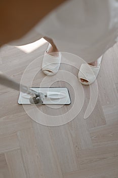 Close up angle of person feet and mop head, mopping and cleaning the floor of the house.