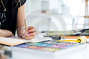 Close-up angle view of a female painter drawing draft at sketchbook using pencil. Artist sketching in art studio with photo